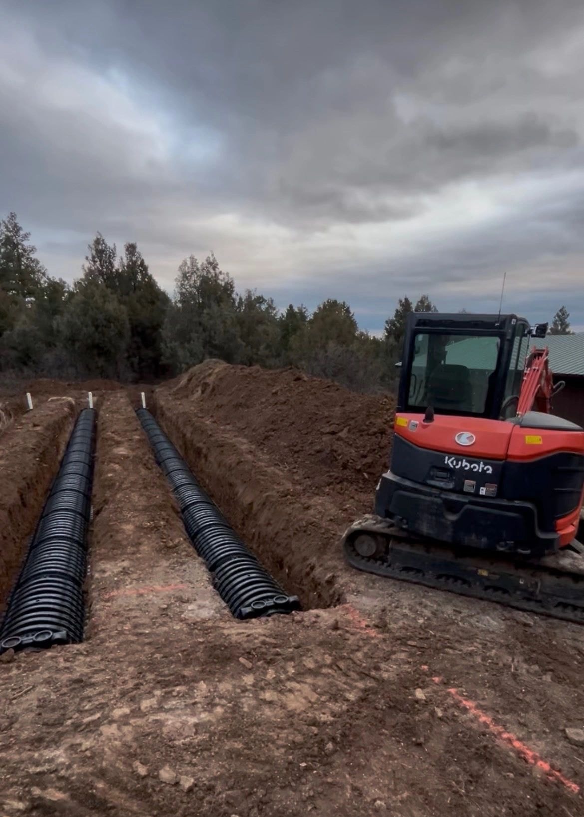 Kubota excavator with drainage pipes on site